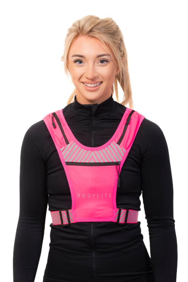 A person wearing a neon pink phone holder vest with reflective straps and detailing, designed for visibility during workouts.