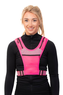 A person wearing a neon pink phone holder vest with reflective straps and detailing, designed for visibility during workouts.