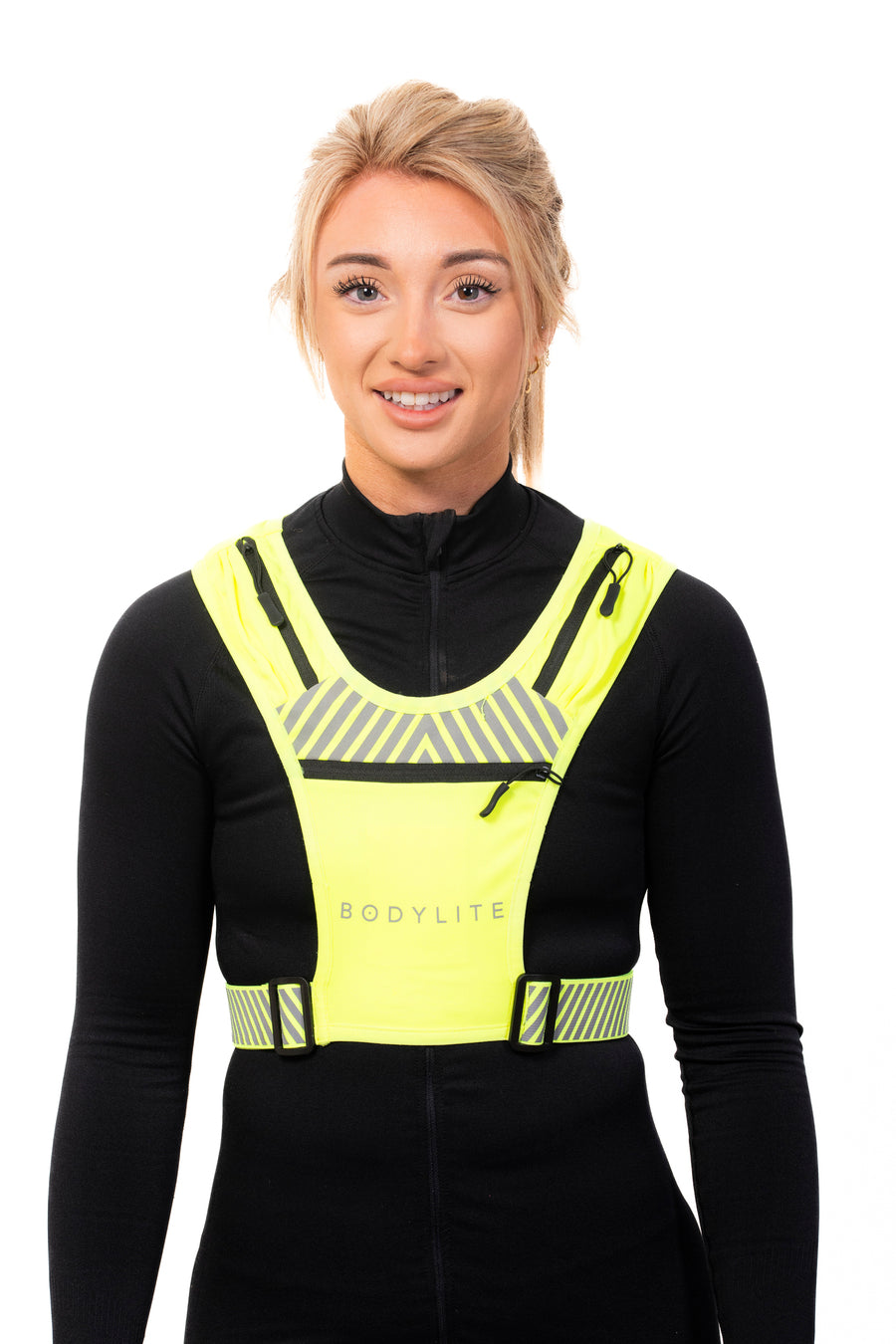 A person wearing a neon yellow phone holder vest with reflective straps and detailing, designed for visibility during workouts.